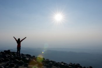 Silhouette of Young woman standing on top of cliff in summer mountains at sunset and enjoying view of nature viewpoint of the knob stone ground, Phu Hin Rong Kla National Park, Leadership Concept.. Woman on cliff of mountains.