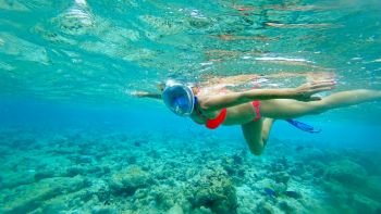 The girl in a mask under water the Indian Ocean with corals and fish
