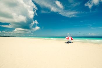 Beautiful beach of Varadero during a sunny day, fine white sand and turquoise and green Caribbean sea,on the right one red parasol,Cuba.concept  photo,copy space,vintage style.