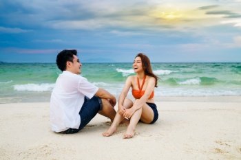 happy young couple sitting on the sea beach at Koh MunNork Island, Rayong, Thailand
