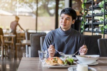 young man eating with food in restaurant