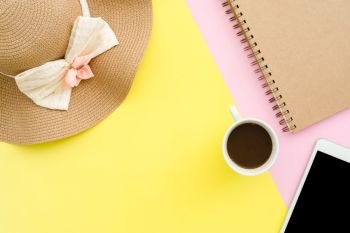 Flat lay design of travel in summer concept - Top view mock up of a summer hat, notebook, coffee and tablet on pink yellow pastel color screen copy space. travel on summer on pastel color background.
