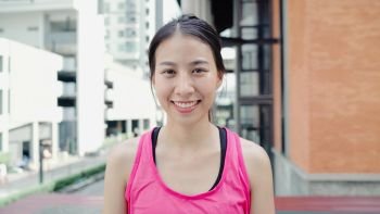 Healthy beautiful young Asian runner woman feeling happy smiling and looking to camera after running on street in urban city. Lifestyle fit and active women exercise in the city concept.