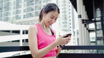 Healthy beautiful young Asian Athlete woman using smartphone for listen to music while running in urban city. Lifestyle women exercise in the city concept.