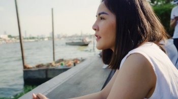 Young Asian woman blogger tourist with casual look at front of port and boat on the river feel relaxing happy joyful travel at cafe at city town , Lifestyle tourist travel holiday concept.