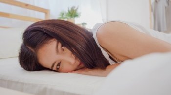 Asian woman smiling lying on bed in bedroom, Beautiful japanese female using relax time after wake up at home. Lifestyle women using relax time at home concept.