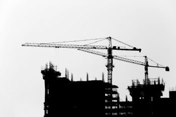 Silhouette crane a building under construction on white background.