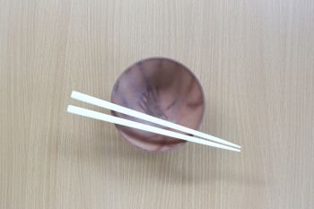 White chopsticks and bowl in top view on wood background for design concept food.