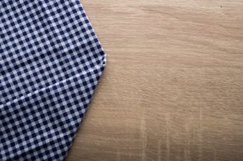Checkered blue napkin on wooden background.. Checkered blue napkin on wooden background.
