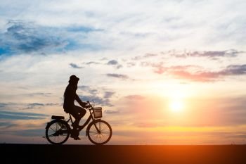 Young man ride bicycle on sunset background.