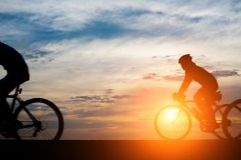 Young man ride bicycle on sunset background.