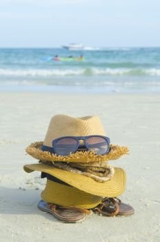 Summer beach bag with straw hat,towel,sunglasse s and flip flops on sandy beac