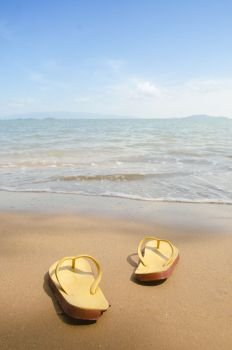 Yellow beach slippers on sandy beach, summer, bathing