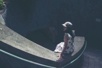 Young girl traveler sitting on circle stairs of a spiral staircase of an underground crossing in tunnel at Fort Canning Park, Singapore