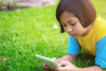 Asian girls are using tablet on lawn in the park.