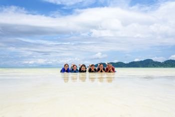 Asian people group adult and teens are family, Happy life enjoy by lying together on the beach of Ra Wi island during the sea travel vacation in summer holiday at Ko Lipe, Tarutao, Satun, Thailand. Happy family lying together on the beach, Thailand