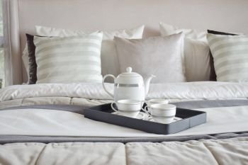 Decorative tray of tea set on the bed in modern bedroom interior