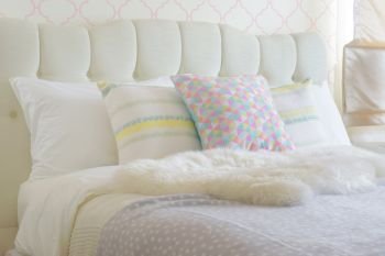 Sweet colorful pillows setting on bed with puffy scarf