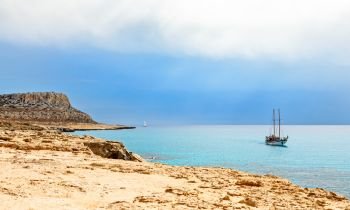 Cape Greco panorama with blue sea and yacht in the foreground, Agia Napa, Cyprus