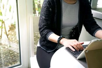 Young student women wearing smart band focus on her tablet computer and smart phone