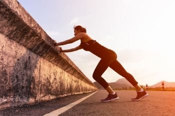 sport woman runner stretching muscle before run on the long road