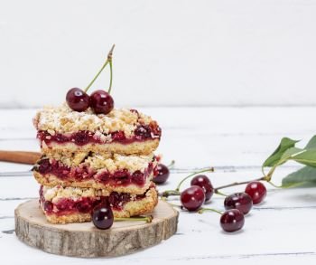 stack of baked cake with cherry berries on a wooden board, white table