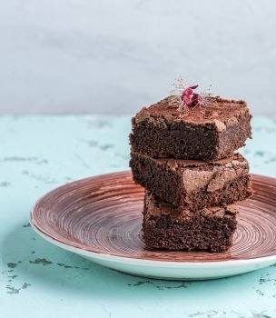 stack of square pieces of baked brownies on a round ceramic plate