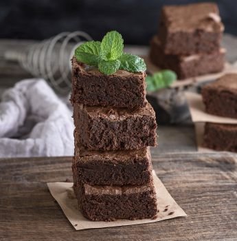 stack of square pieces of baked brown brownie pie on a wooden  board