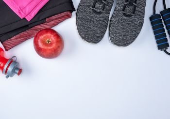 black textile shoes and other items for fitness on a white background, top view