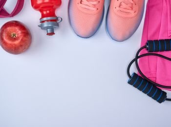 pink sports sneakers and a red water bottle, black jump rope on a white background, top view, copy space