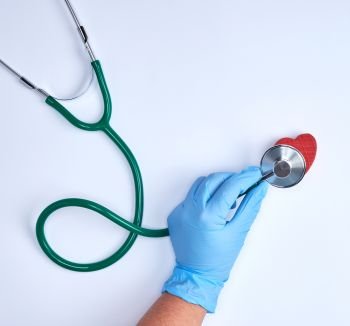 human hand in blue sterile gloves holding a green stethoscope, mdicine background