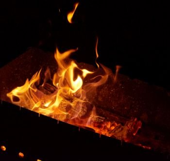 burning wooden logs in the fire at night, black background 