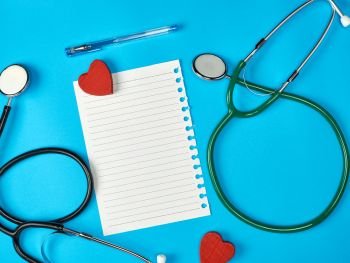 blank white piece of paper in a line and a medical stethoscope on a blue background