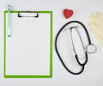 black medical stethoscope and green paper holder on a white background, copy space