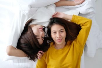 LGBT, Young cute asia lesbians lying and smiling on white bed together in the morning, couple lesbians happy moment 