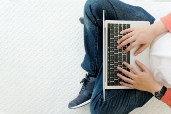 Man using laptop computer while sitting on white floor background with copy space, top view, people and technology, lifestyles