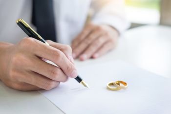 Closeup of a man Signing Contract or premarital agreement, filling petition form agreement of divorce in office at lawyer desk in court room  Conceptual of marriage.