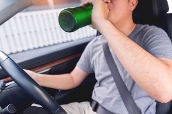 Don’t Drink for Drive concept, Young Drunk man drinking bottle of beer or alcohol during driving the car dangerously.
