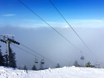 Gondolas from the ski lift in Koessen in tyrol austria on the mountain Unterberghorn appear as the clouds. Ski lift in Koessen at Unterberghorn