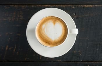 Heart Shape Froth Milk Latte Art in White Coffee Cup on Black Wood Table. Heart shape froth milk Latte art hot beverage for coffee lover