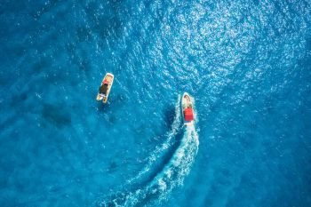 Motorboat at the sea in balearic islands. Aerial view of floating boat with people in transparent blue water at bright day. Summer seascape. Top view from drone. Seascape with yacht in motion in bay