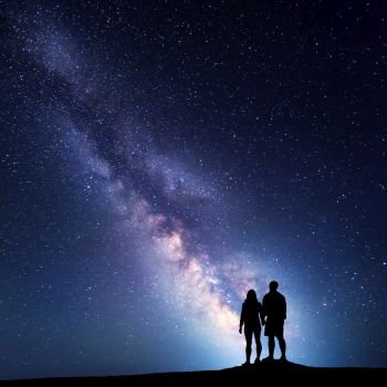 Milky Way with people on the mountain. Landscape with night sky with stars and silhouette of standing  man and woman. Milky way with couple. Travelers against beautiful galaxy. Universe
