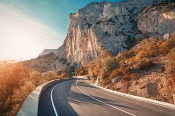 Asphalt road. Colorful landscape with beautiful mountain road with a perfect asphalt. High rocks, blue sky at sunrise in summer. Vintage toning. Travel background. Highway at mountains. Speed