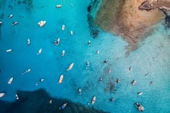 Aerial view of boats and luxury yachts in transparent blue sea at sunny day in Spain. Colorful landscape with marina bay, azure water. Balearic islands. Top view. Travel in Europe. Summer vacation