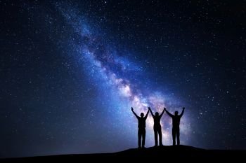 Landscape with colorful Milky Way and silhouette of a happy family with raised-up arms on the mountain. Night starry sky. Beautiful Universe. Space background