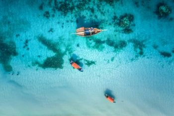 Aerial view of the fishing boats in clear blue water at sunny day in summer. Top view from drone of boat, sandy beach. Indian ocean in Zanzibar, Africa. Landscape with sailboats, clear sea. Seascape