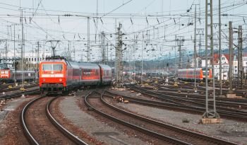 Railway station with modern red commuter train  in motion in the evening in Nuremberg, Germany. Red train on the railroad track with vintage toning