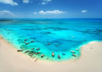 Aerial view of the fishing boats on tropical sea coast with sandy beach at sunny day. Summer holiday. Indian Ocean, Zanzibar, Africa. Landscape with boat, white sand, azure water, blue sky. Top view