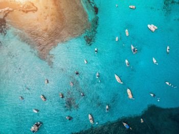 Aerial view of boats and luxury yachts in transparent blue sea at sunset in Spain. Colorful landscape with marina bay, azure water. Balearic islands. Top view. Travel in Europe. Summer vacation