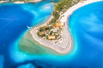 Aerial view of sandy beach with umbrellas, green forest at sunny day in summer. Blue lagoon in Oludeniz, Turkey. Tropical landscape with sea bay, island, white sandy bank, blue water. Top view. Nature